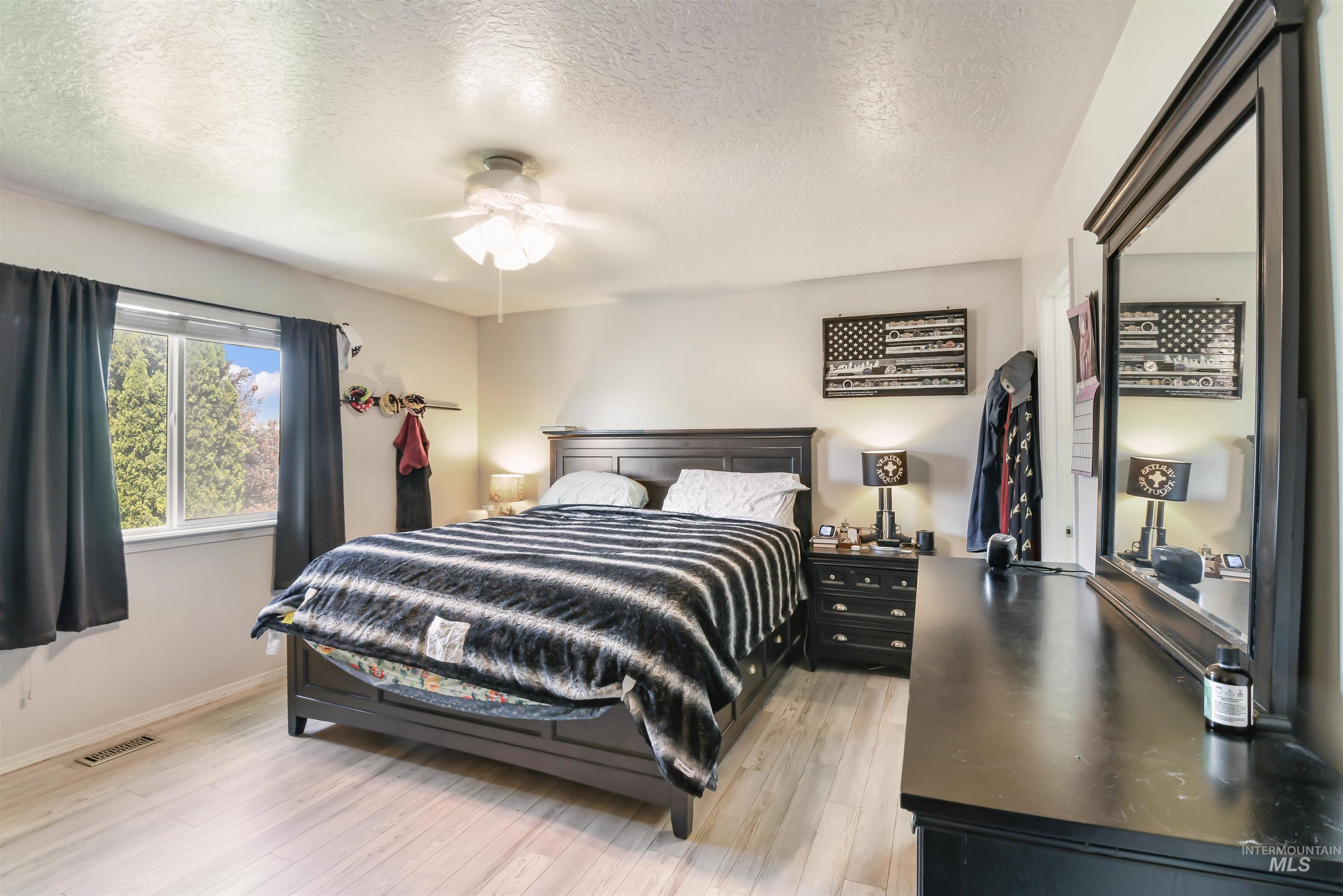 Bedroom with light wood finished floors, a textured ceiling, and a ceiling fan