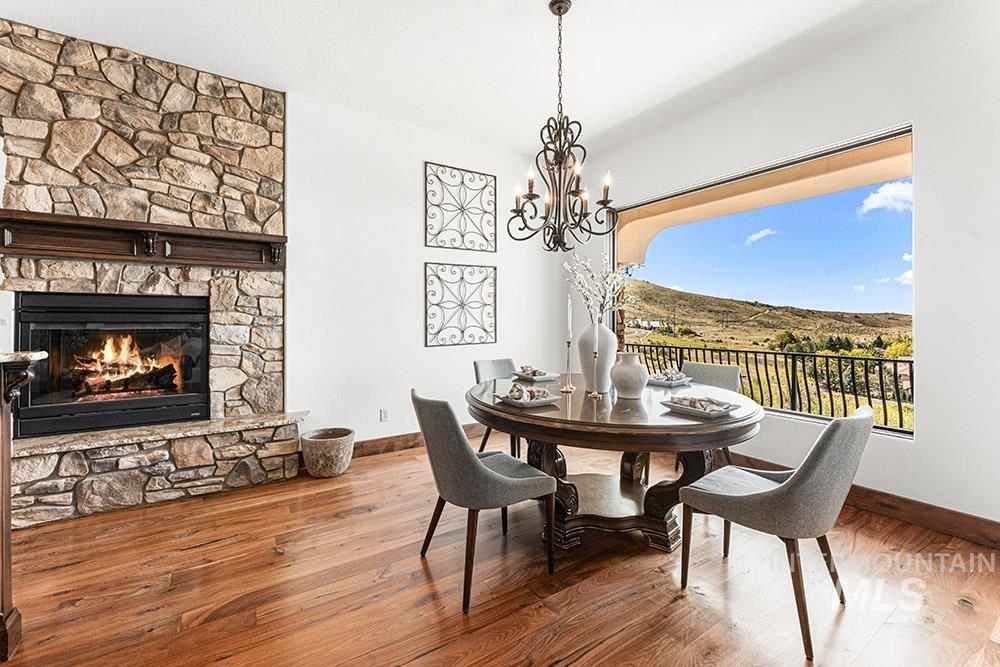 Dining room with wood-type flooring, a stone fireplace, and a chandelier