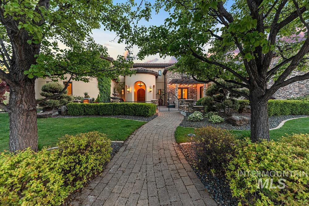 Mediterranean / spanish home featuring a gate, stucco siding, a fenced front yard, a tile roof, and stone siding