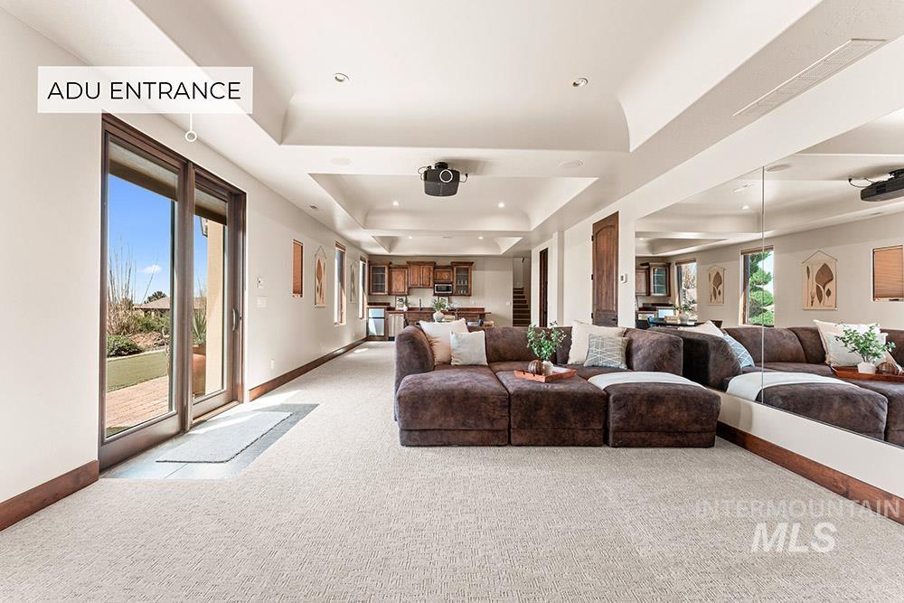 Living area with a tray ceiling, light colored carpet, and recessed lighting