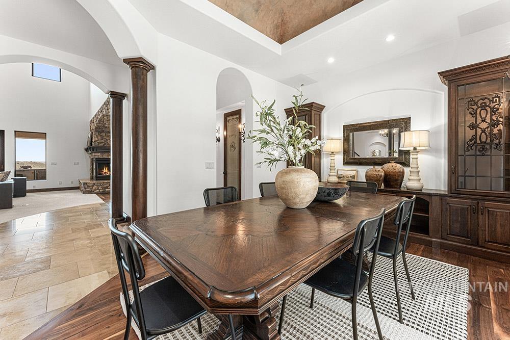 Dining room with arched walkways, ornate columns, a stone fireplace, recessed lighting, and a high ceiling