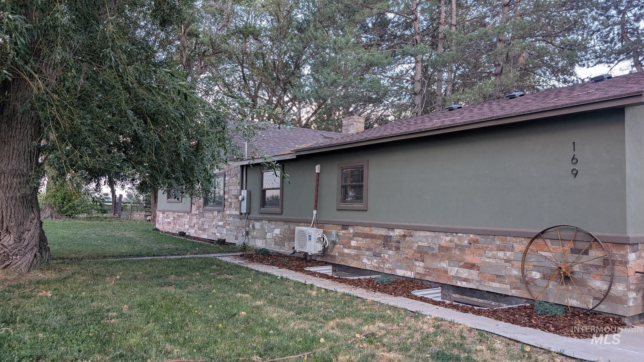 View of home's exterior featuring stone siding, a yard, stucco siding, and roof with shingles