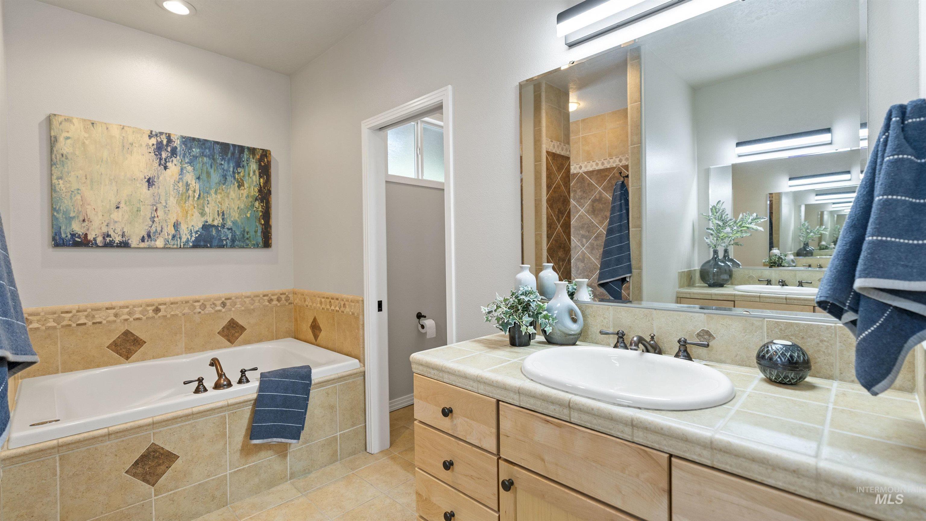 Bathroom with a bath, vanity, tile patterned flooring, and recessed lighting