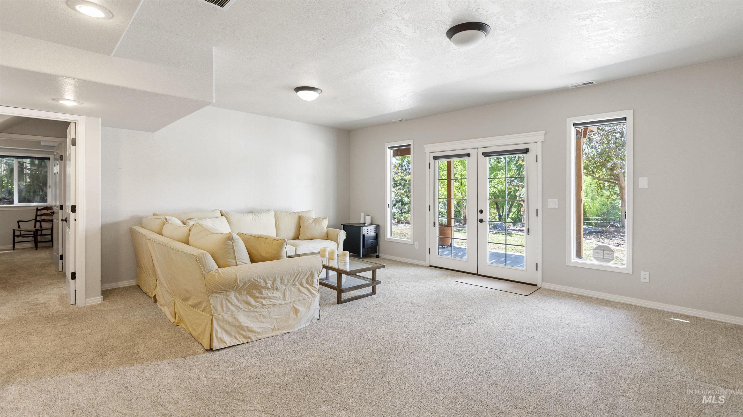 Carpeted living room with healthy amount of natural light, french doors, and a wood stove