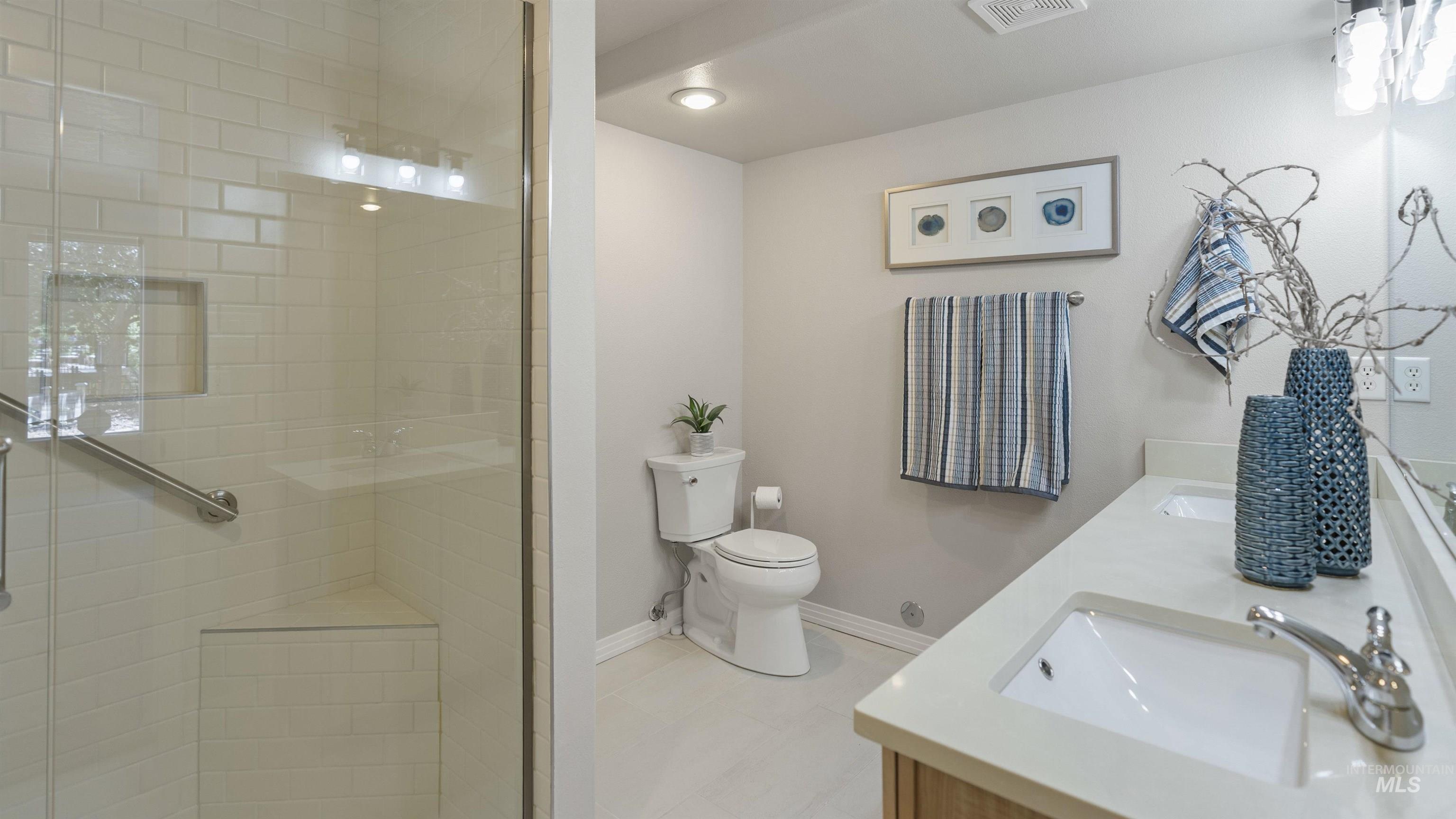 Full bathroom with double vanity and a shower stall