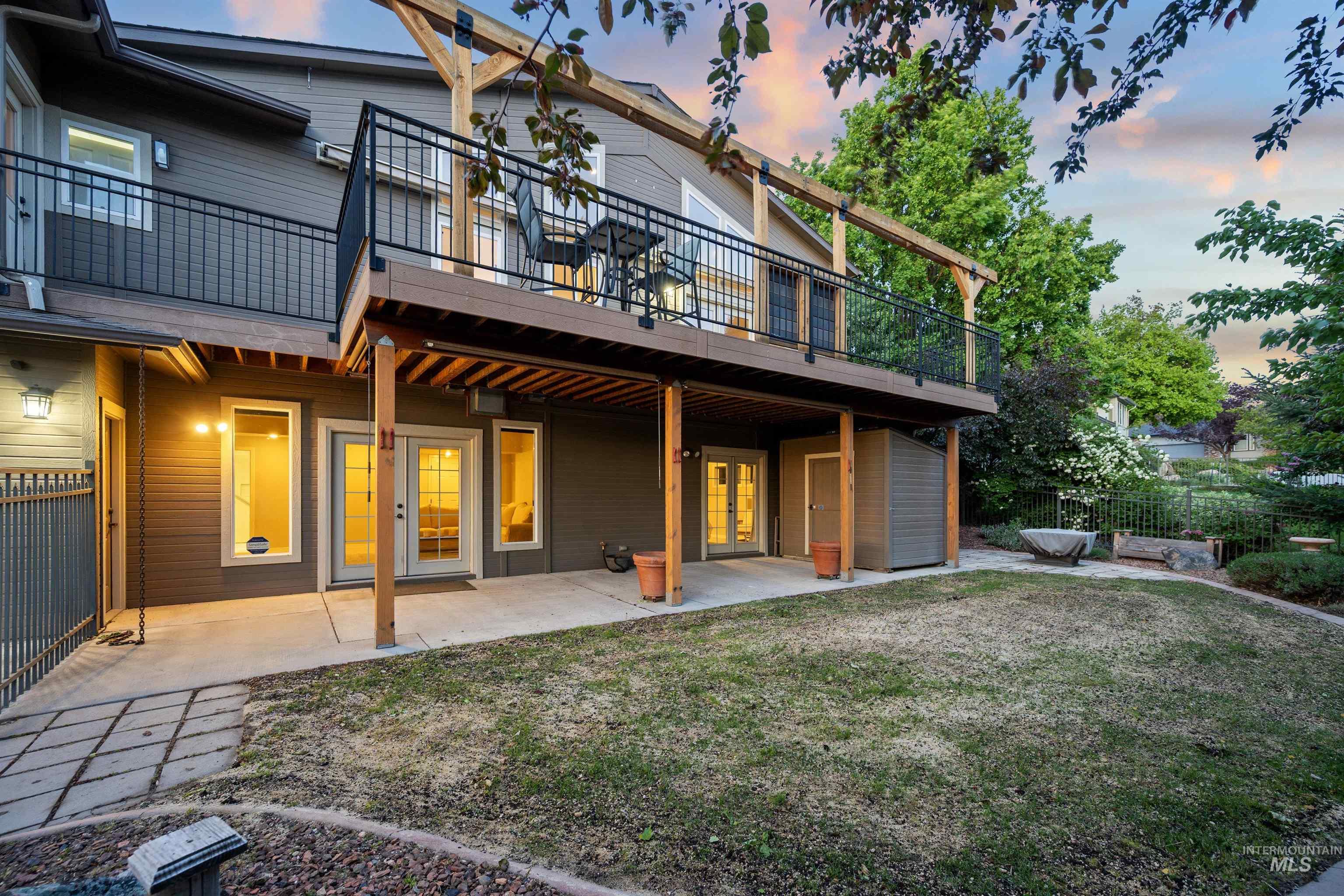Back of property at dusk featuring french doors, a patio, and a deck