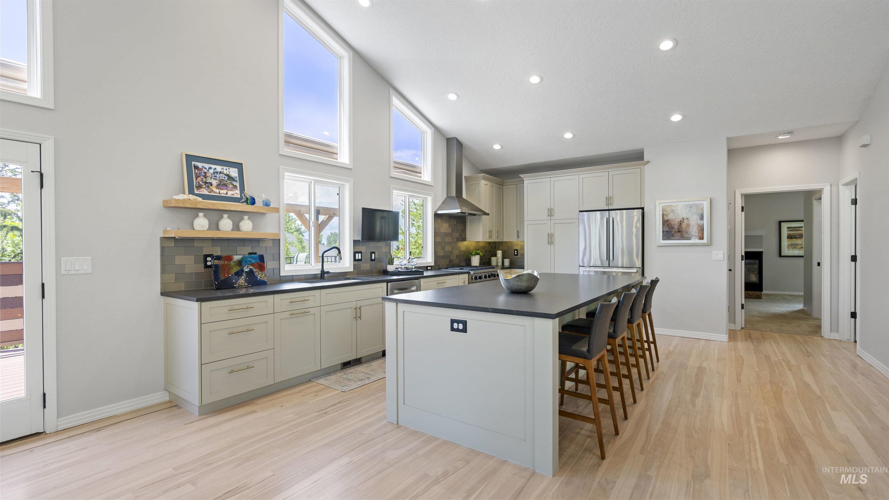 Kitchen with wall chimney range hood, dark countertops, appliances with stainless steel finishes, decorative backsplash, and recessed lighting