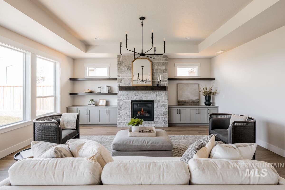Living room with a tray ceiling, plenty of natural light, a fireplace, and wood finished floors