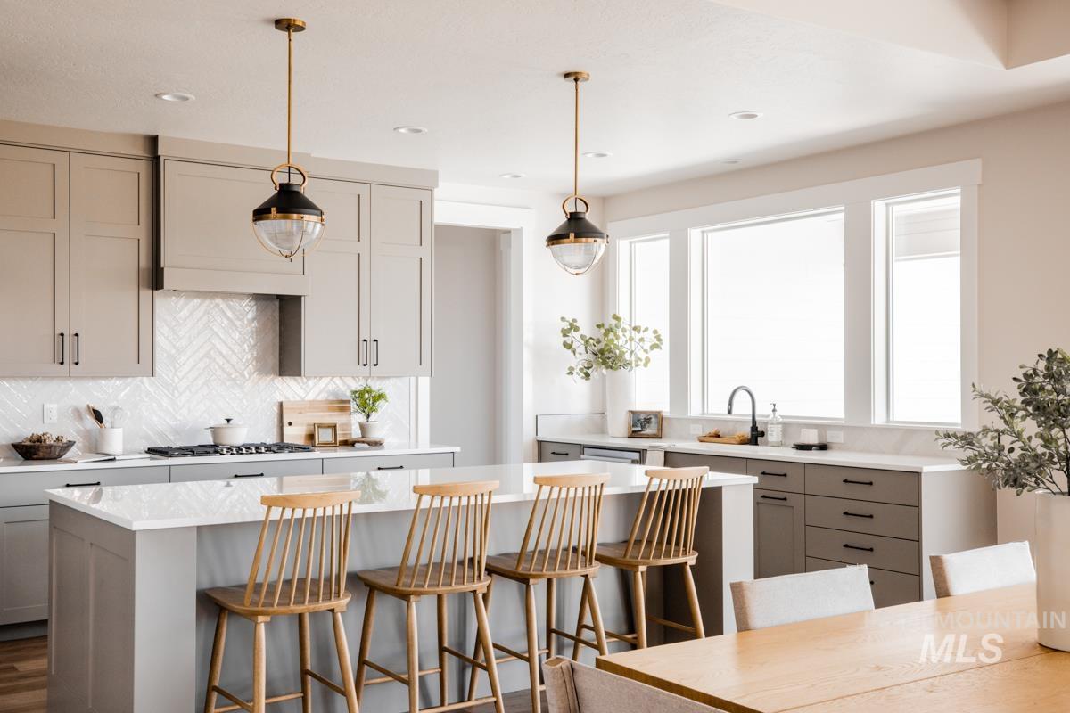 Kitchen with gray cabinetry, light countertops, a center island, backsplash, and a kitchen breakfast bar