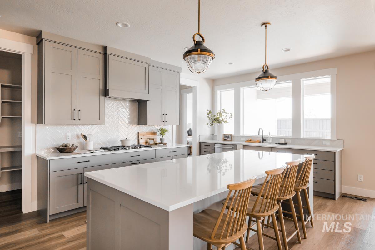 Kitchen featuring gray cabinets, light wood-type flooring, backsplash, a center island, and recessed lighting