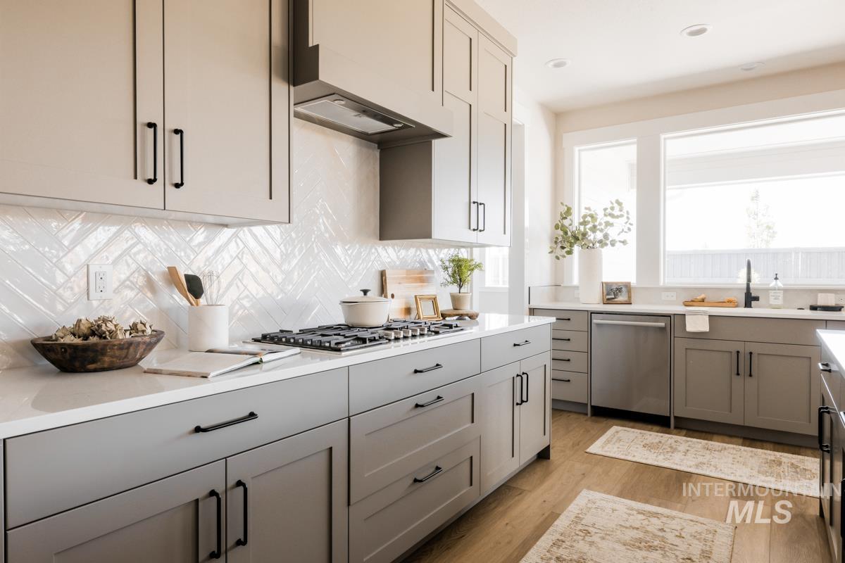 Kitchen with gray cabinetry, decorative backsplash, and stainless steel appliances