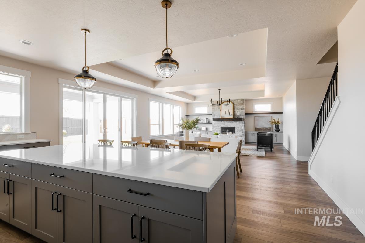 Kitchen with gray cabinets, a raised ceiling, light countertops, dark wood-style floors, and recessed lighting