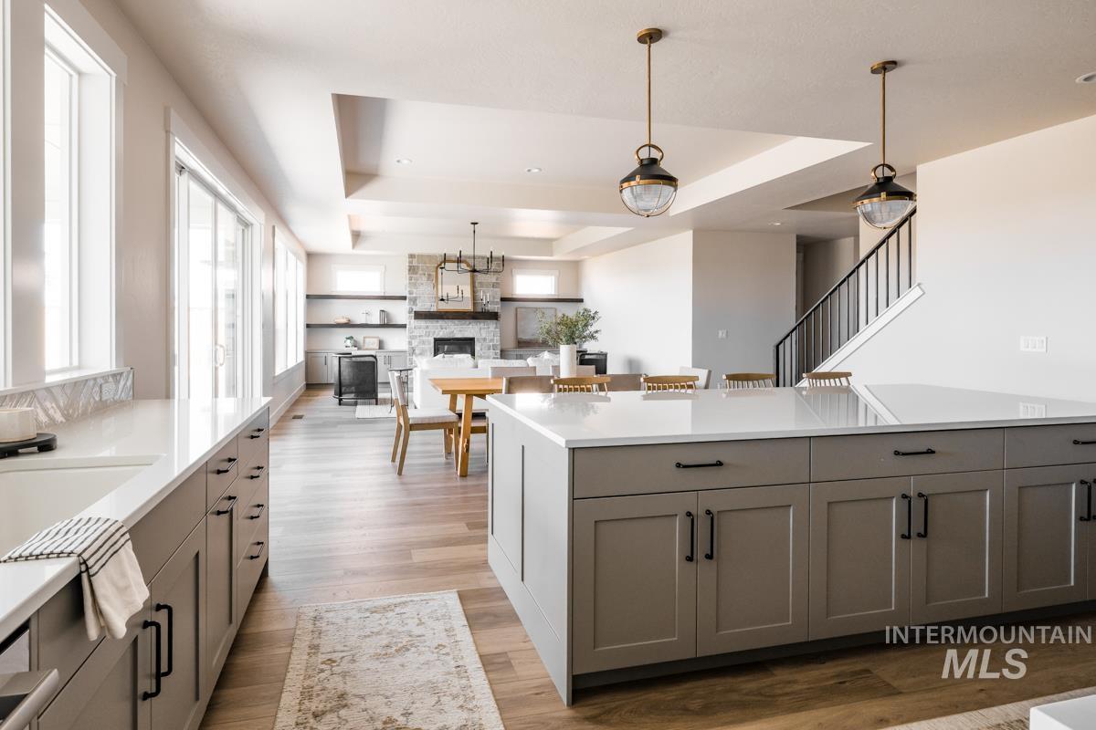 Kitchen featuring gray cabinets, a tray ceiling, tasteful backsplash, light countertops, and recessed lighting