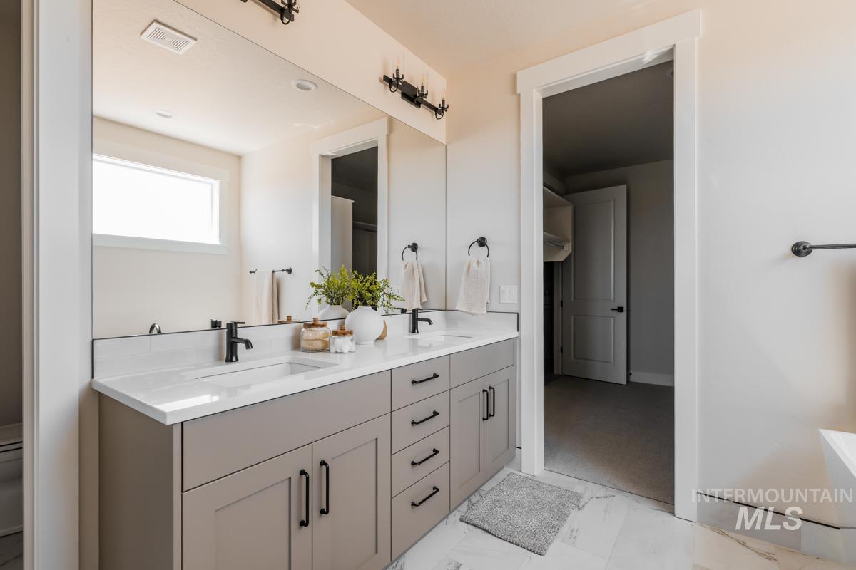 Bathroom featuring double vanity and marble finish flooring