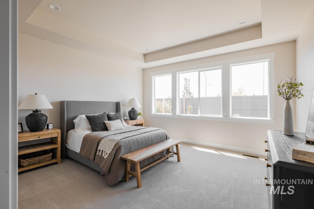 Carpeted bedroom featuring a tray ceiling and baseboards