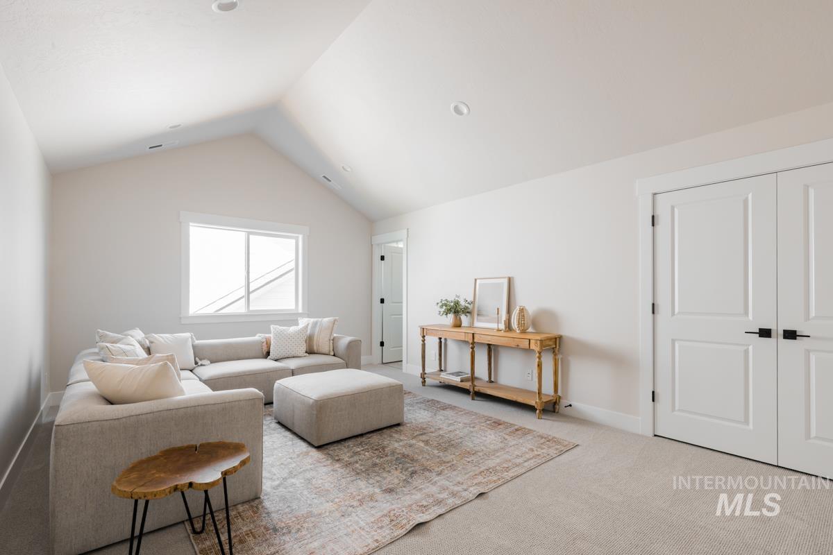 Carpeted living room with lofted ceiling and baseboards