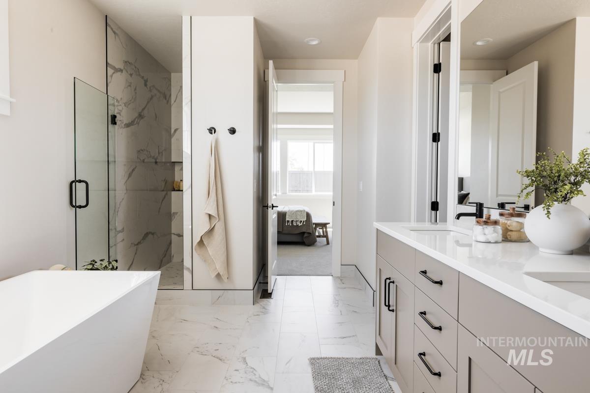 Ensuite bathroom with a marble finish shower, a freestanding bath, double vanity, and marble finish floors