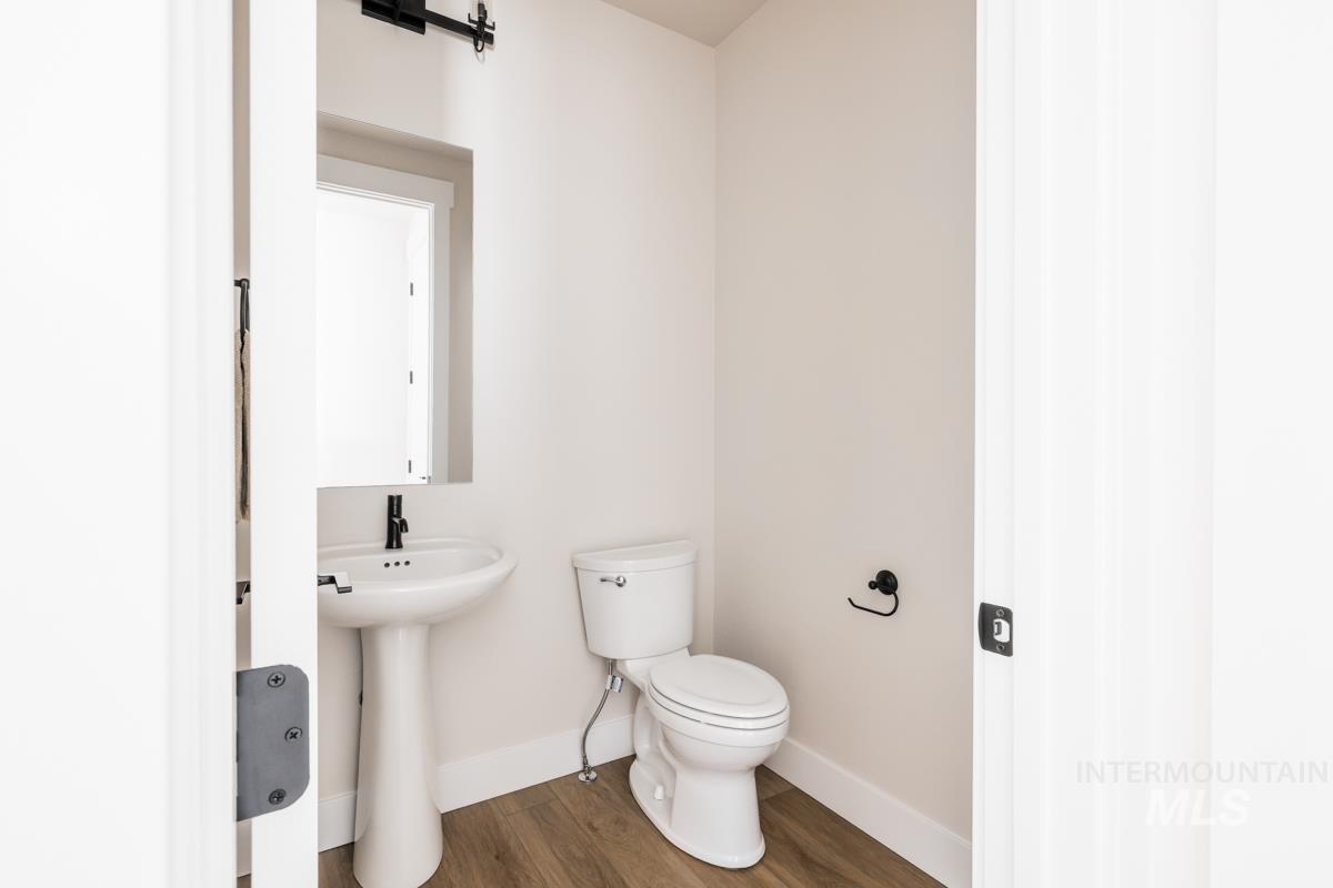 Half bath with baseboards and wood finished floors