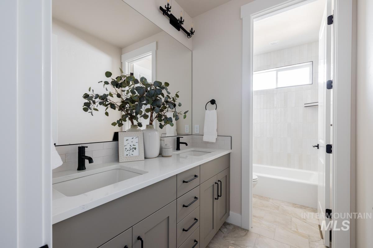 Bathroom with double vanity, decorative backsplash, tub / shower combination, and marble finish floors