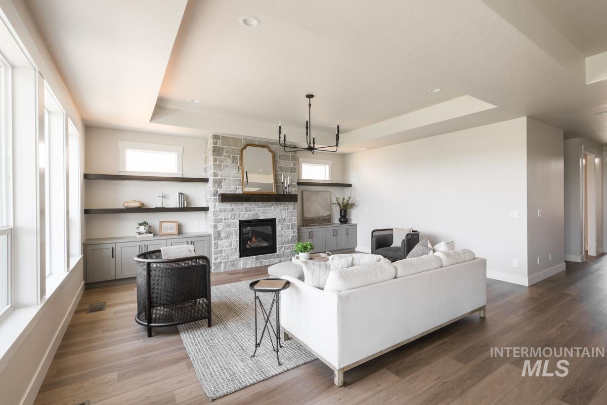 Living area with a tray ceiling, healthy amount of natural light, light wood-style floors, and recessed lighting