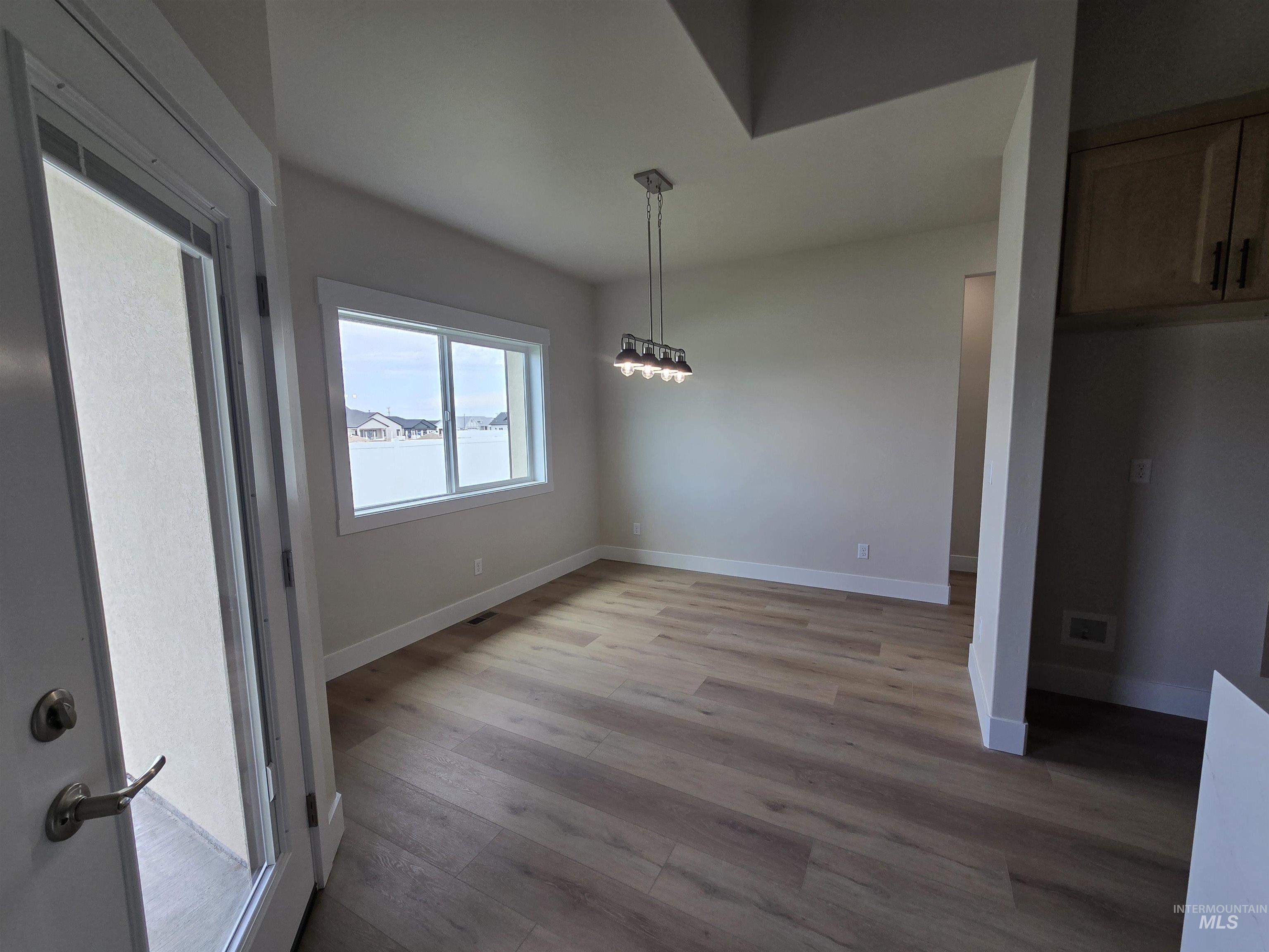 Unfurnished dining area with light wood-type flooring and baseboards