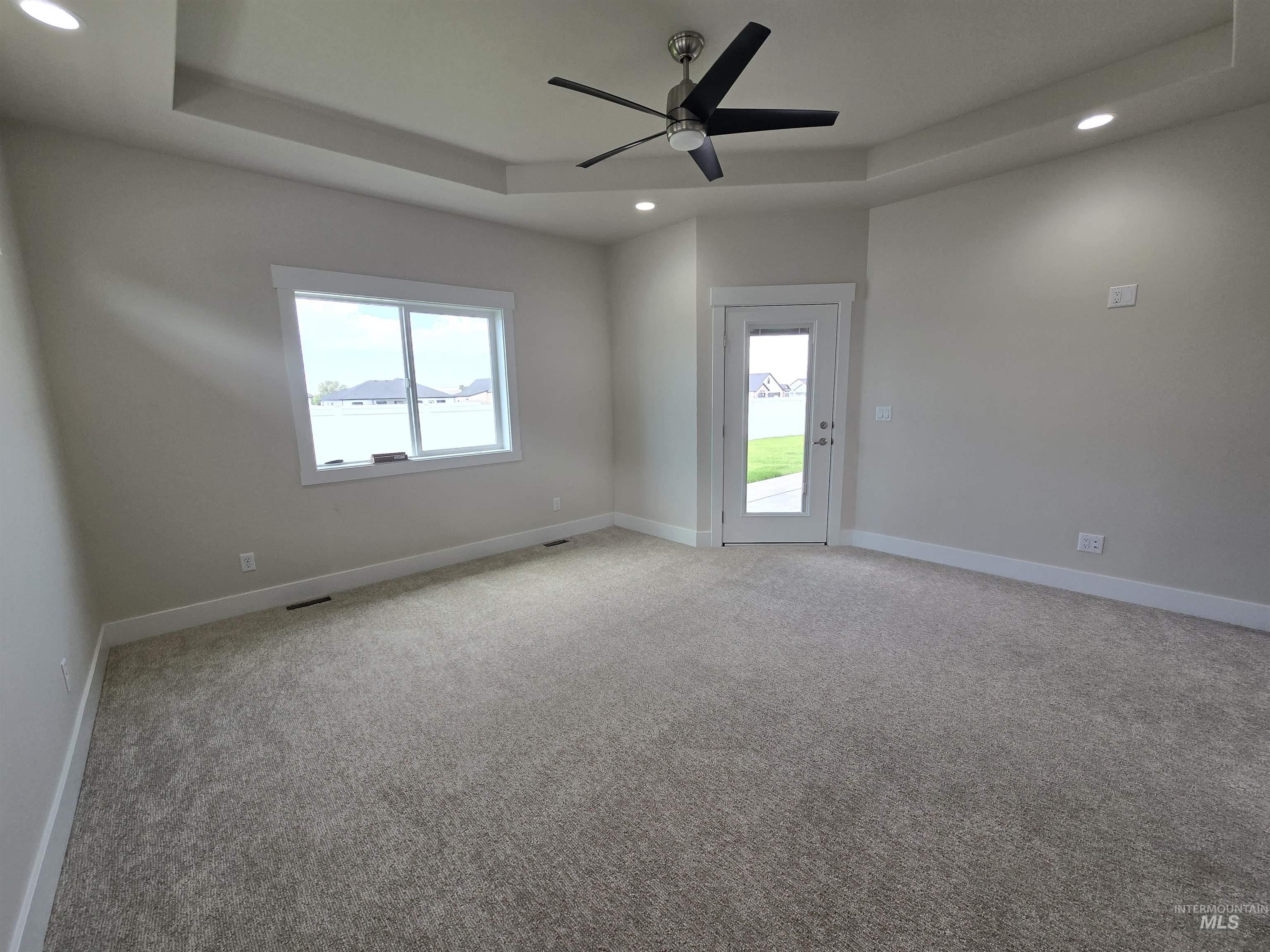 Empty room featuring recessed lighting, a ceiling fan, light carpet, and a tray ceiling
