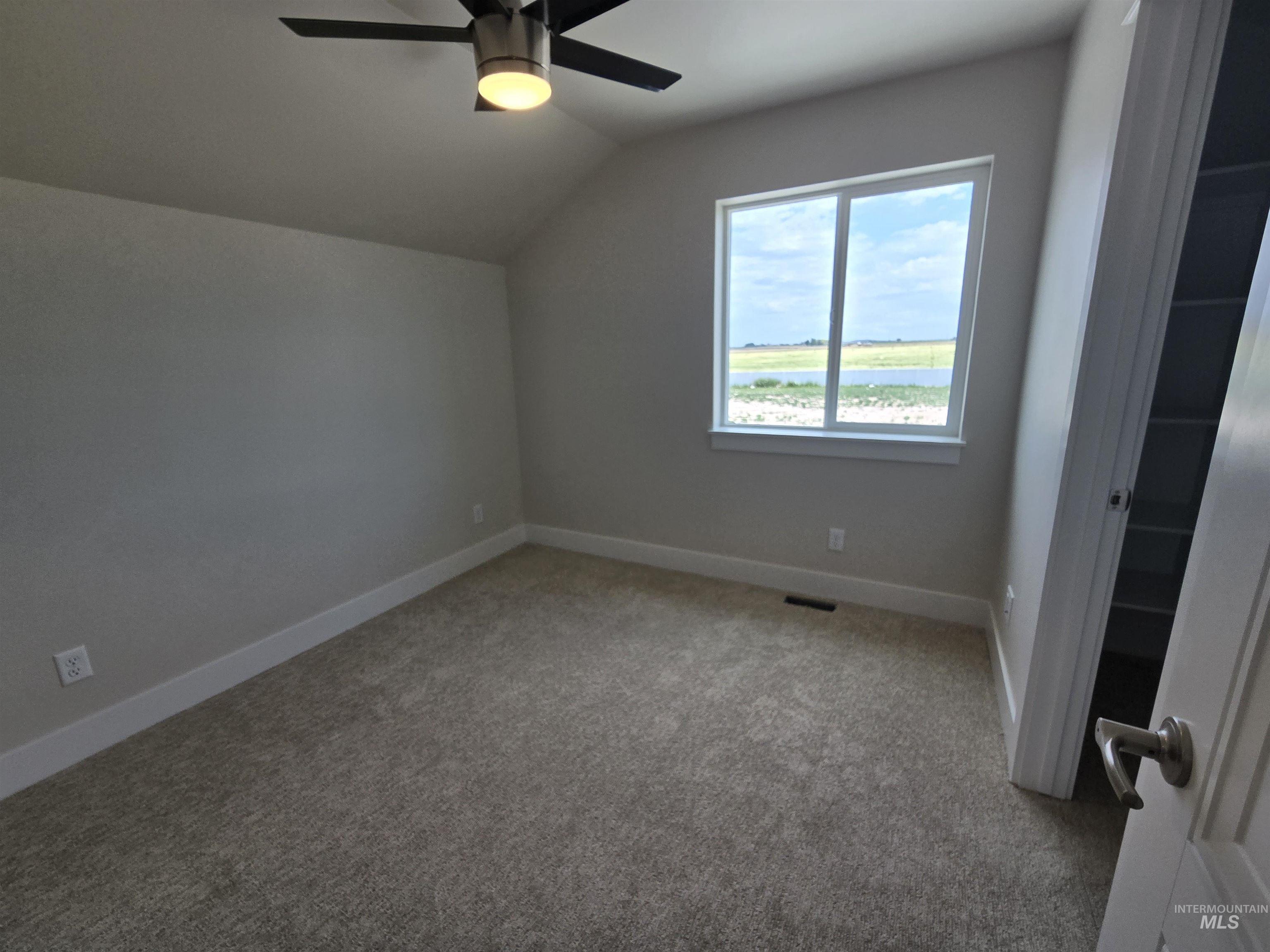 Bonus room with lofted ceiling, light colored carpet, and ceiling fan