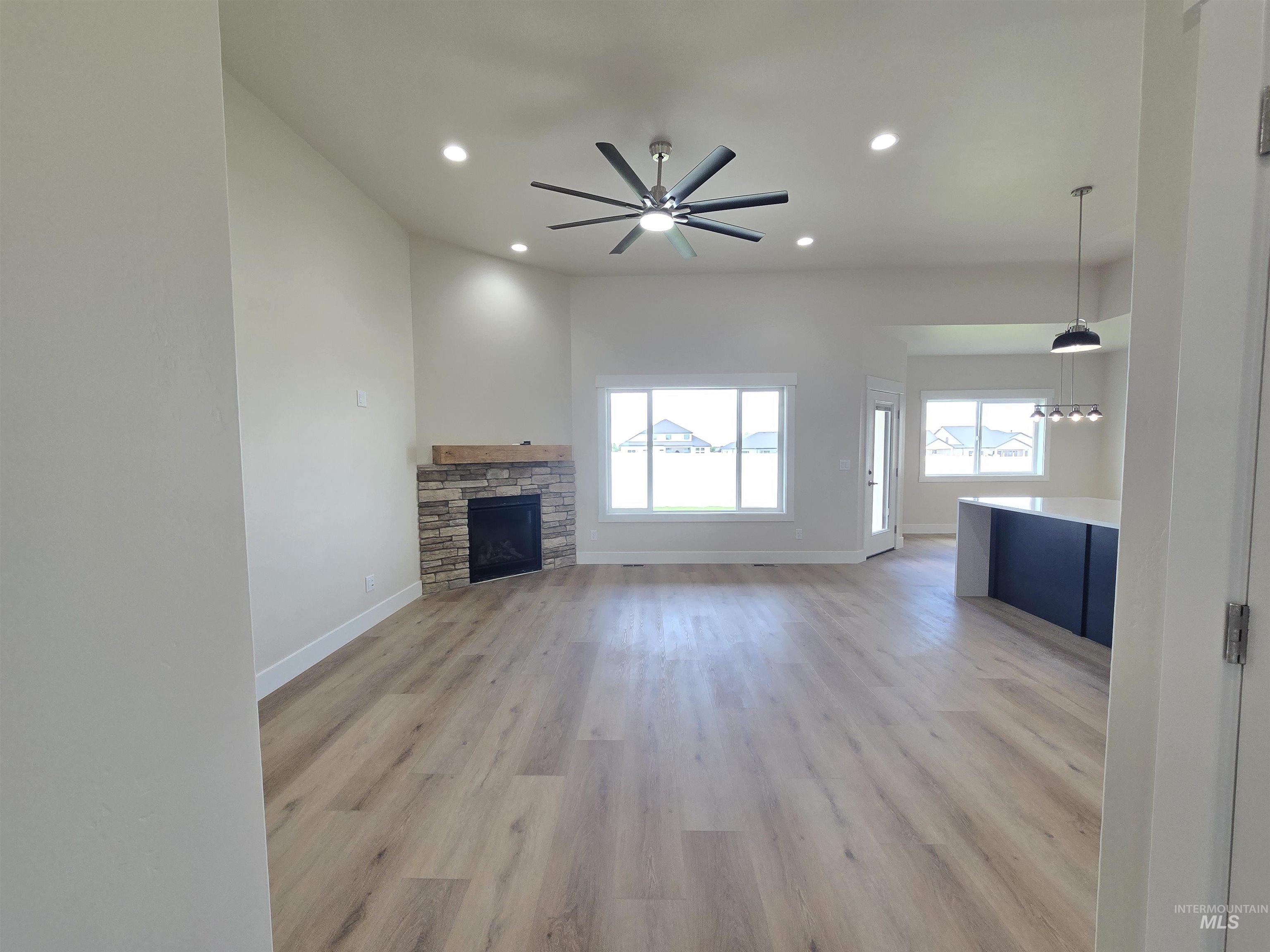 Unfurnished living room with recessed lighting, light wood-type flooring, ceiling fan, and a stone fireplace