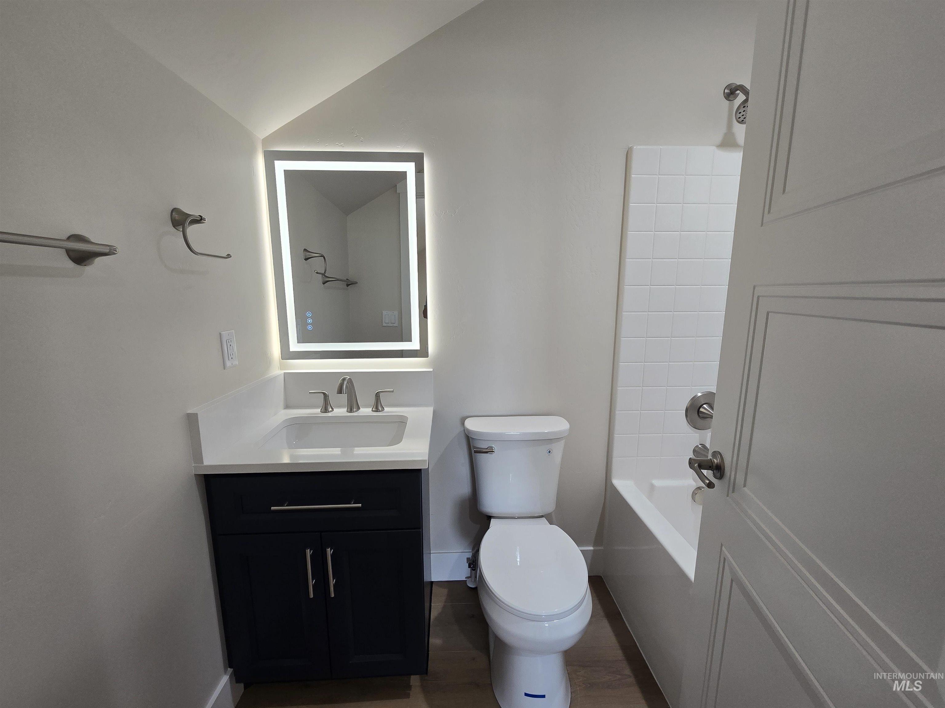 Bathroom with vanity, wood finished floors, and washtub / shower combination