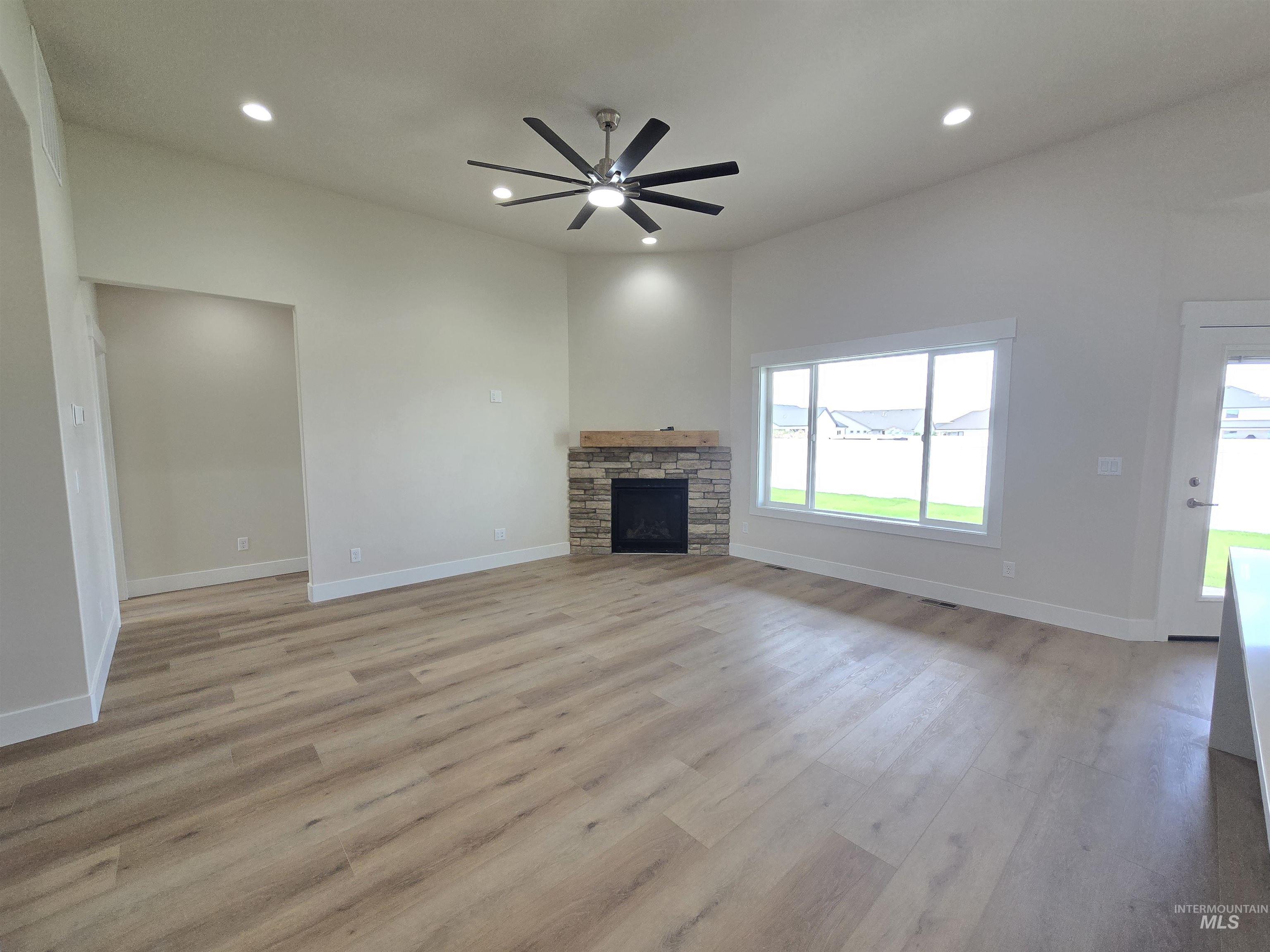 Unfurnished living room featuring ceiling fan, light wood-style floors, recessed lighting, and a stone fireplace