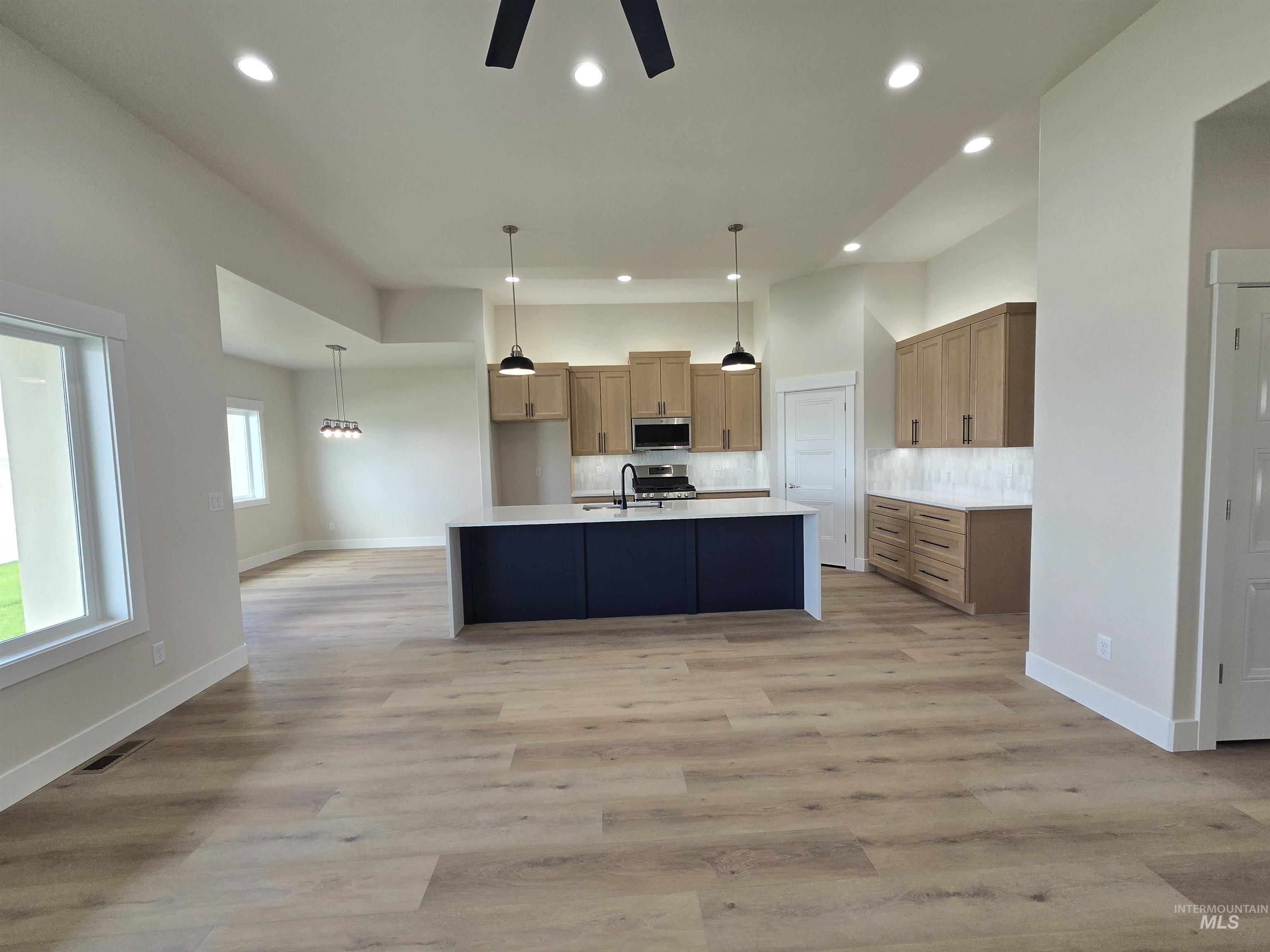 Kitchen featuring appliances with stainless steel finishes, recessed lighting, ceiling fan, decorative backsplash, and light countertops