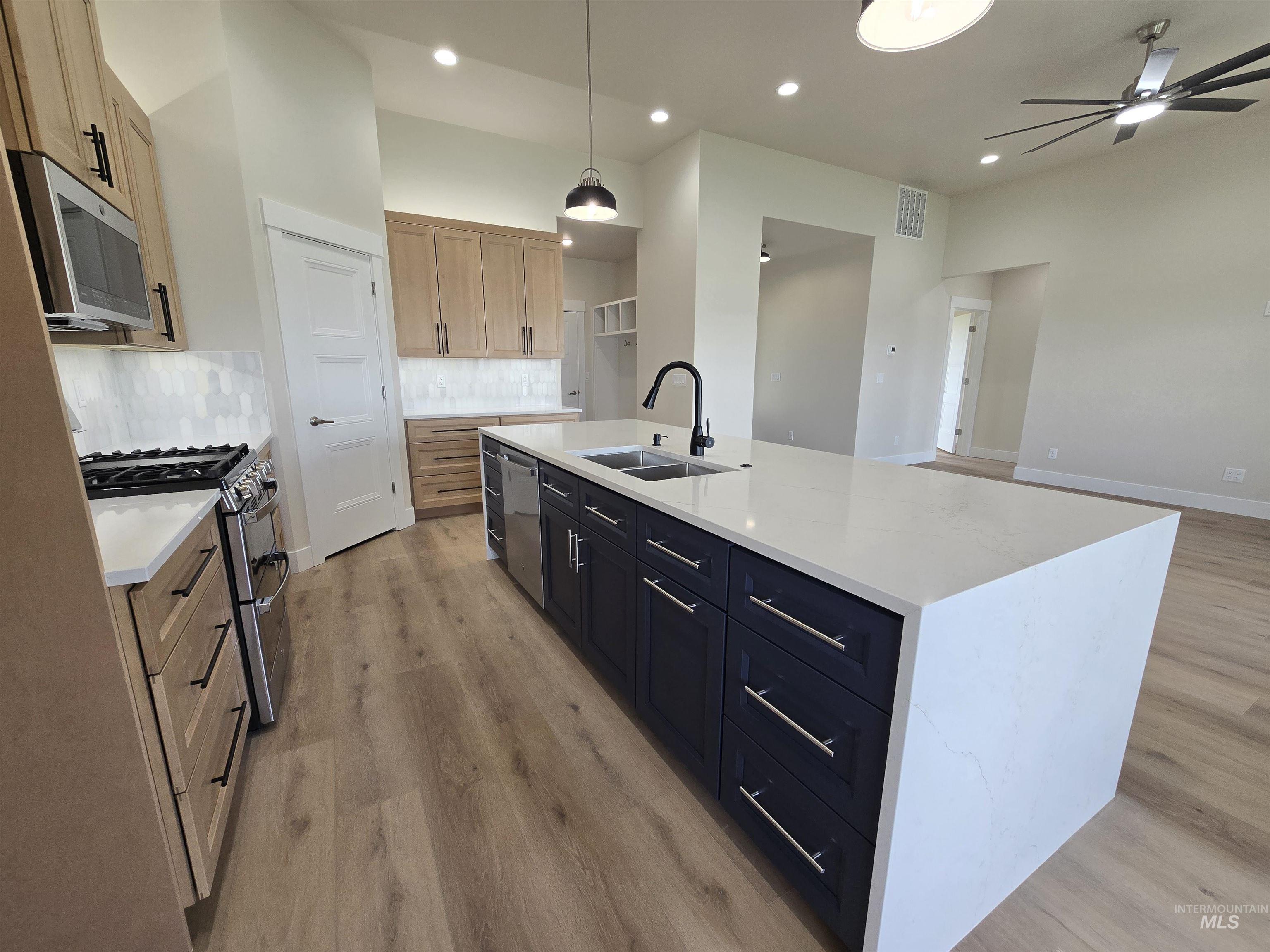 Kitchen featuring stainless steel appliances, light wood-type flooring, ceiling fan, backsplash, and recessed lighting