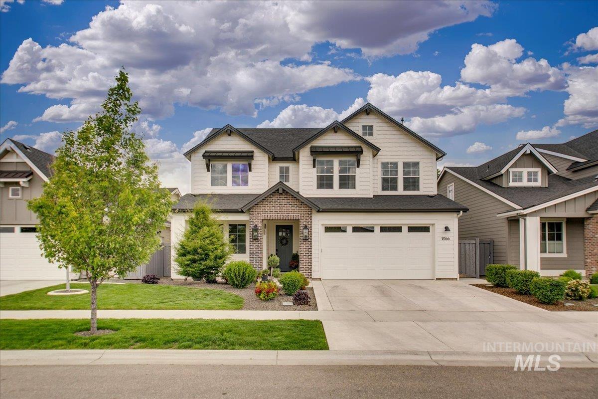 Craftsman-style home featuring concrete driveway, an attached garage, a front yard, brick siding, and a shingled roof