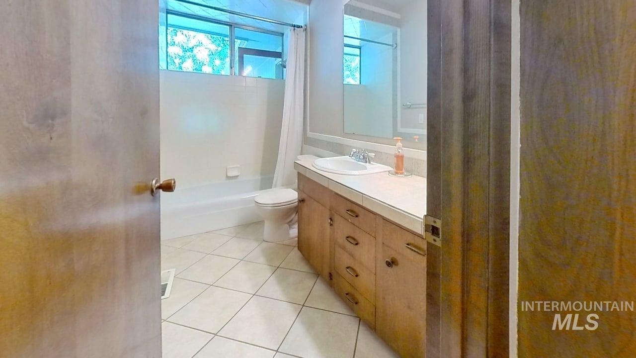 Full bathroom featuring vanity, shower / bath combo with shower curtain, and tile patterned flooring