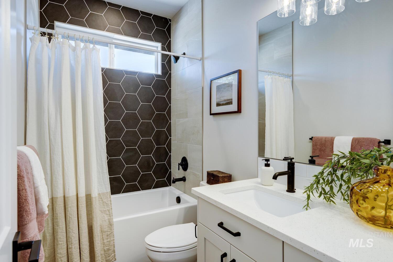 Bathroom featuring vanity and shower / bathtub combination with curtain