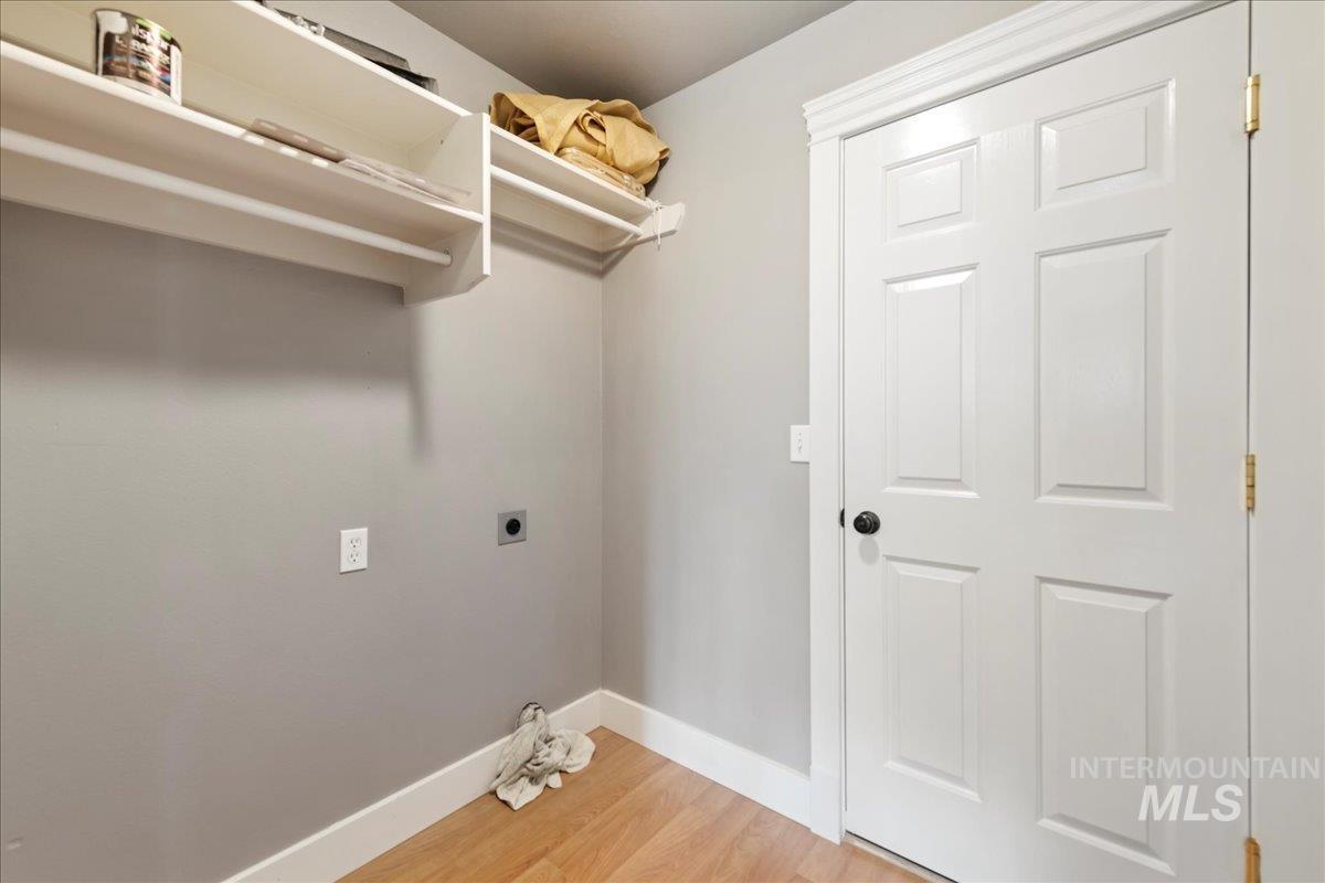 Laundry area featuring electric dryer hookup and light wood-type flooring