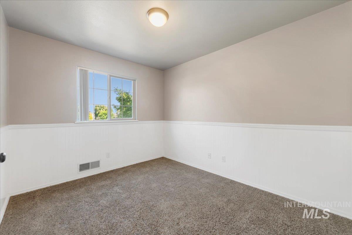 Carpeted spare room featuring wainscoting