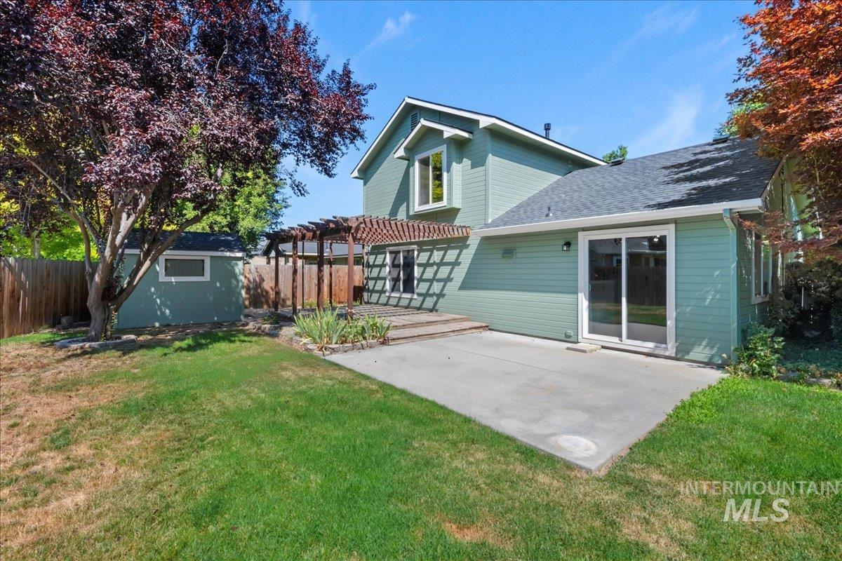 Rear view of property featuring a pergola, a fenced backyard, a patio, roof with shingles, and a storage shed