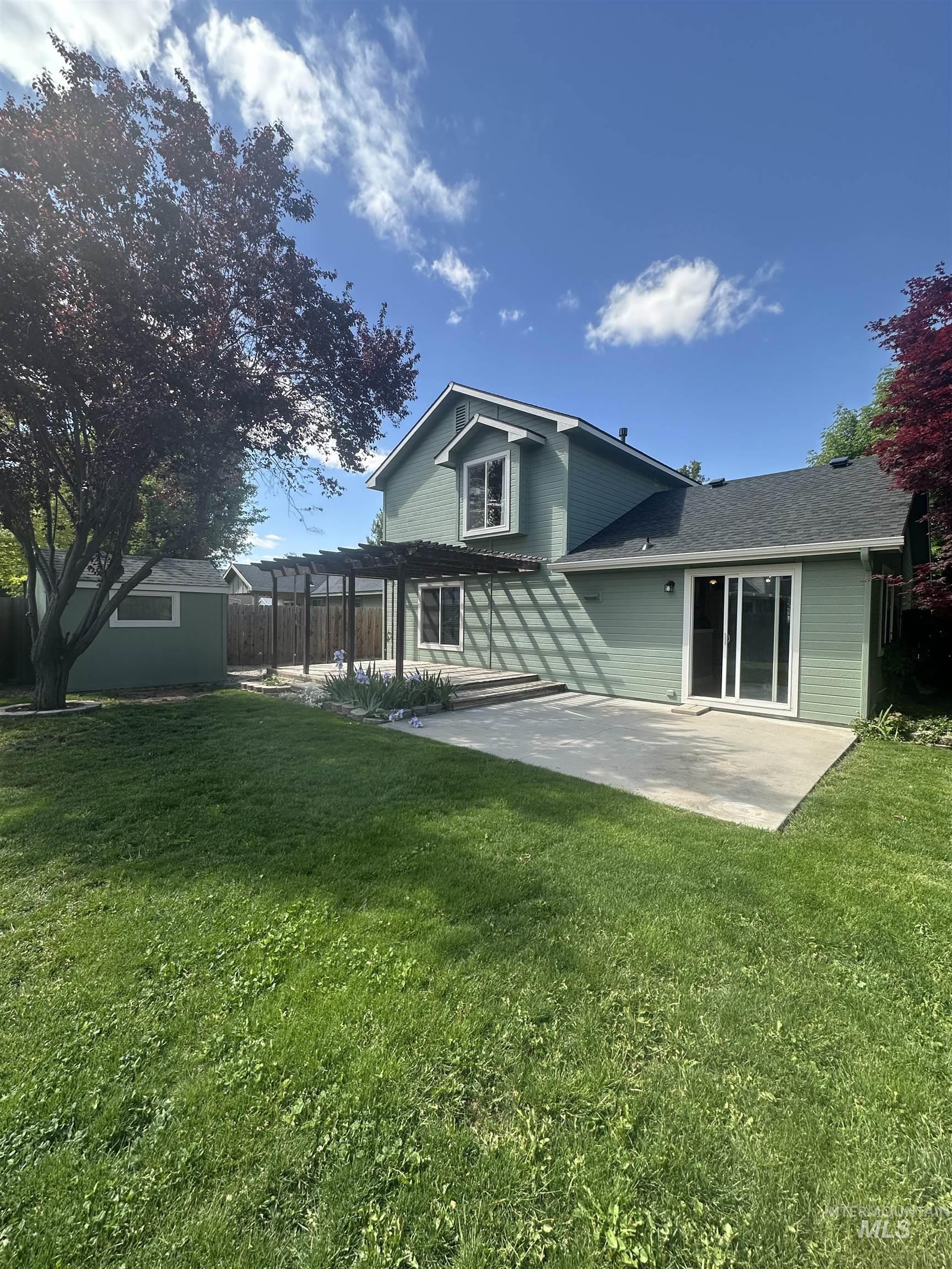 Rear view of house featuring a pergola, a patio area, and a lawn