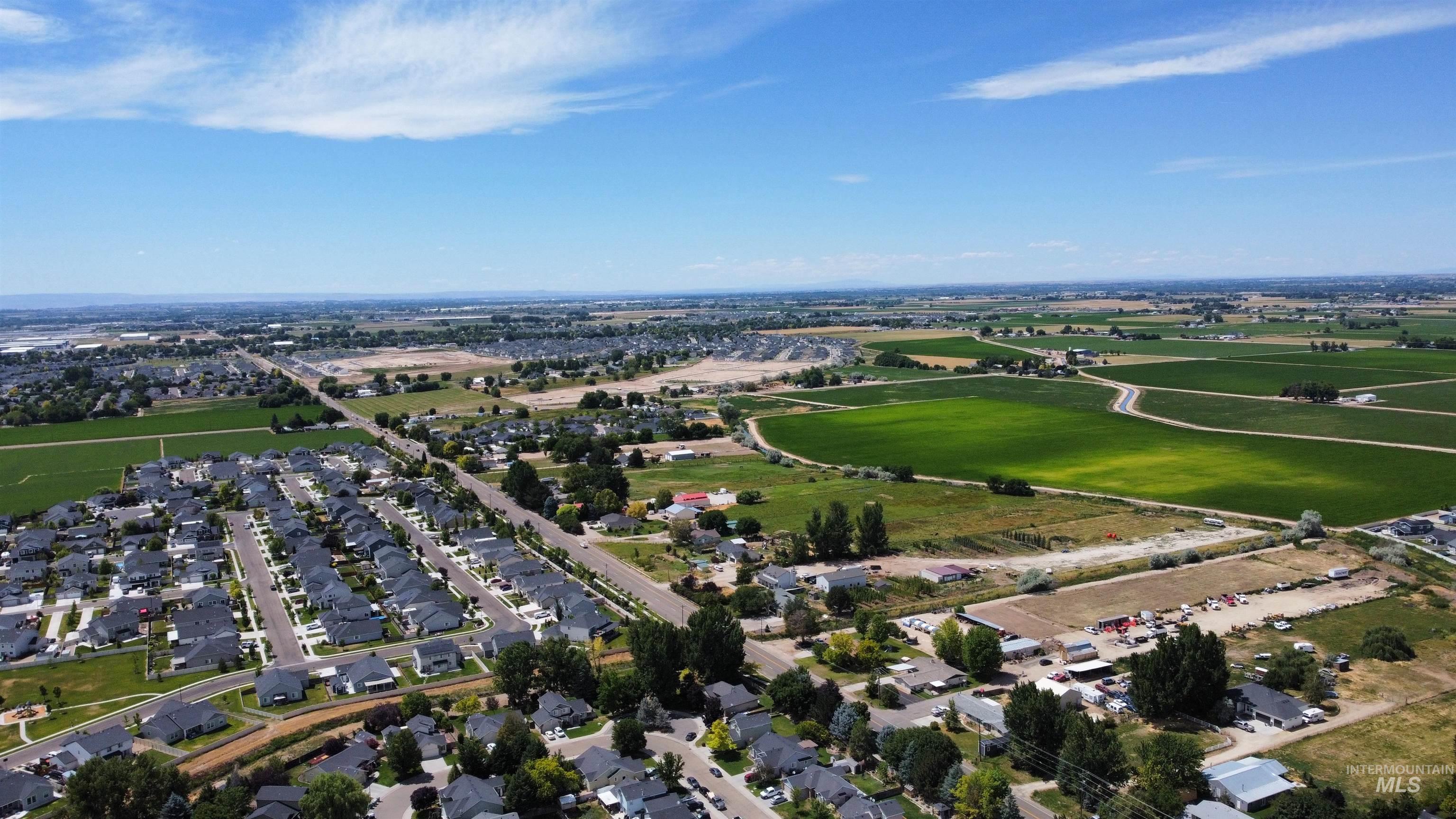 Aerial view of property and surrounding area with nearby suburban area