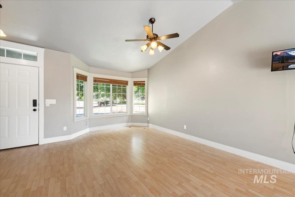 Unfurnished living room with vaulted ceiling, light wood finished floors, and ceiling fan