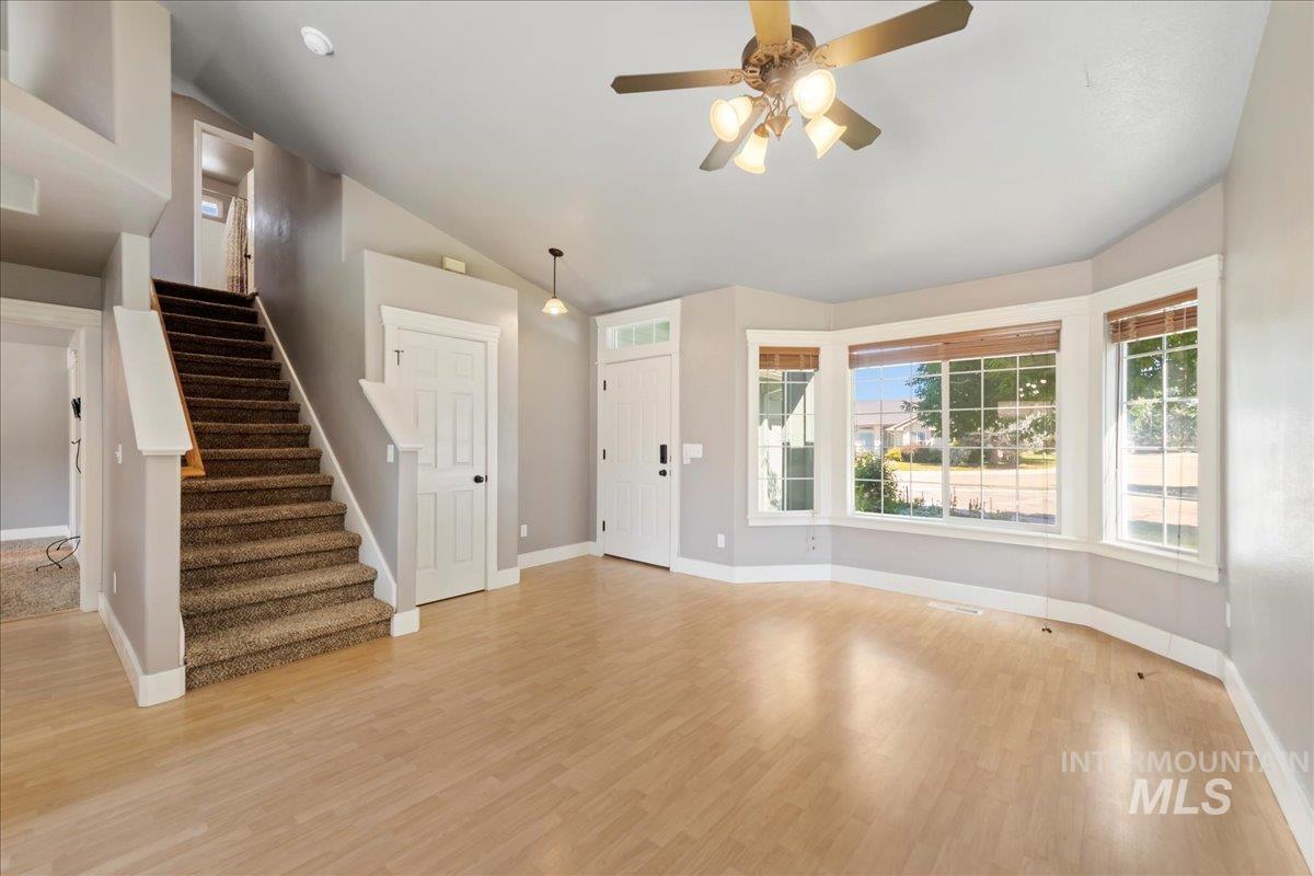 Foyer with lofted ceiling, light wood-type flooring, stairway, and ceiling fan