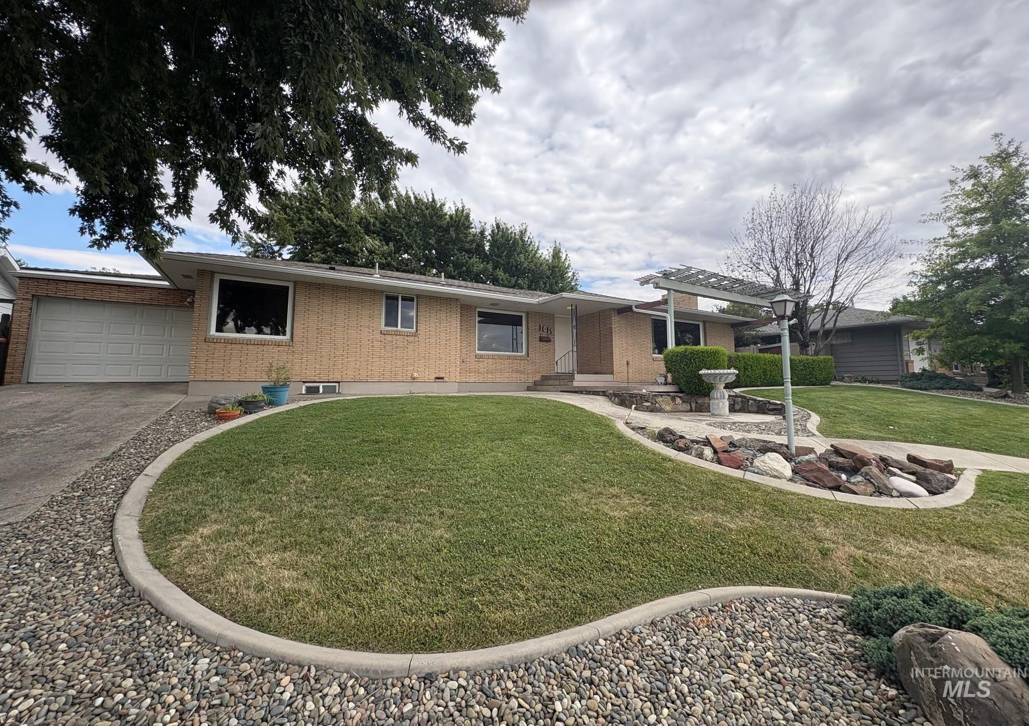 Ranch-style home with brick siding, driveway, a front lawn, and an attached garage