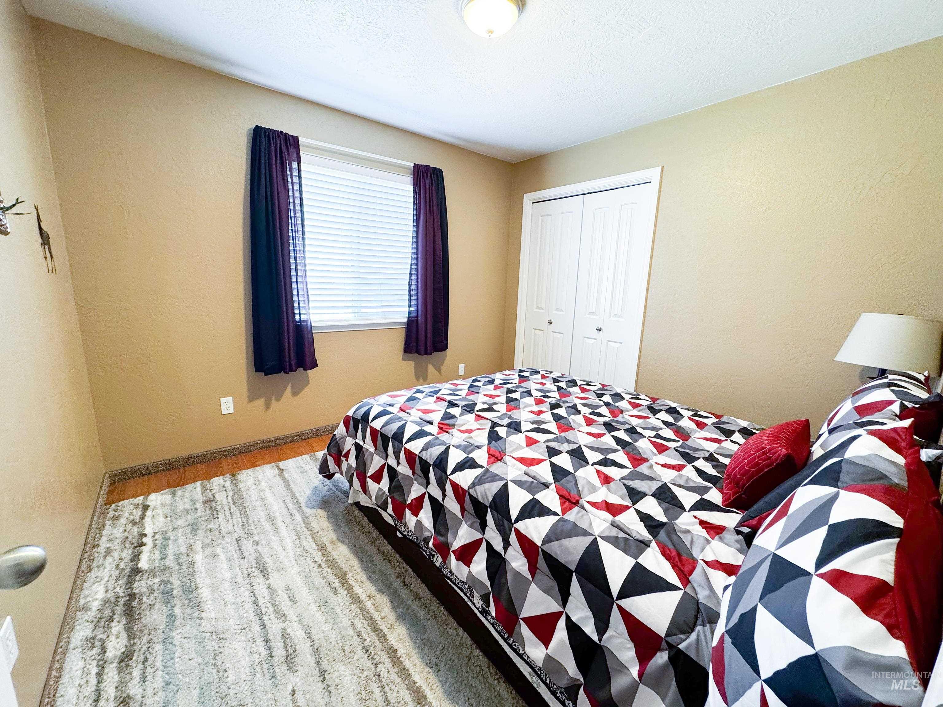 Bedroom with a closet, wood finished floors, and a textured wall
