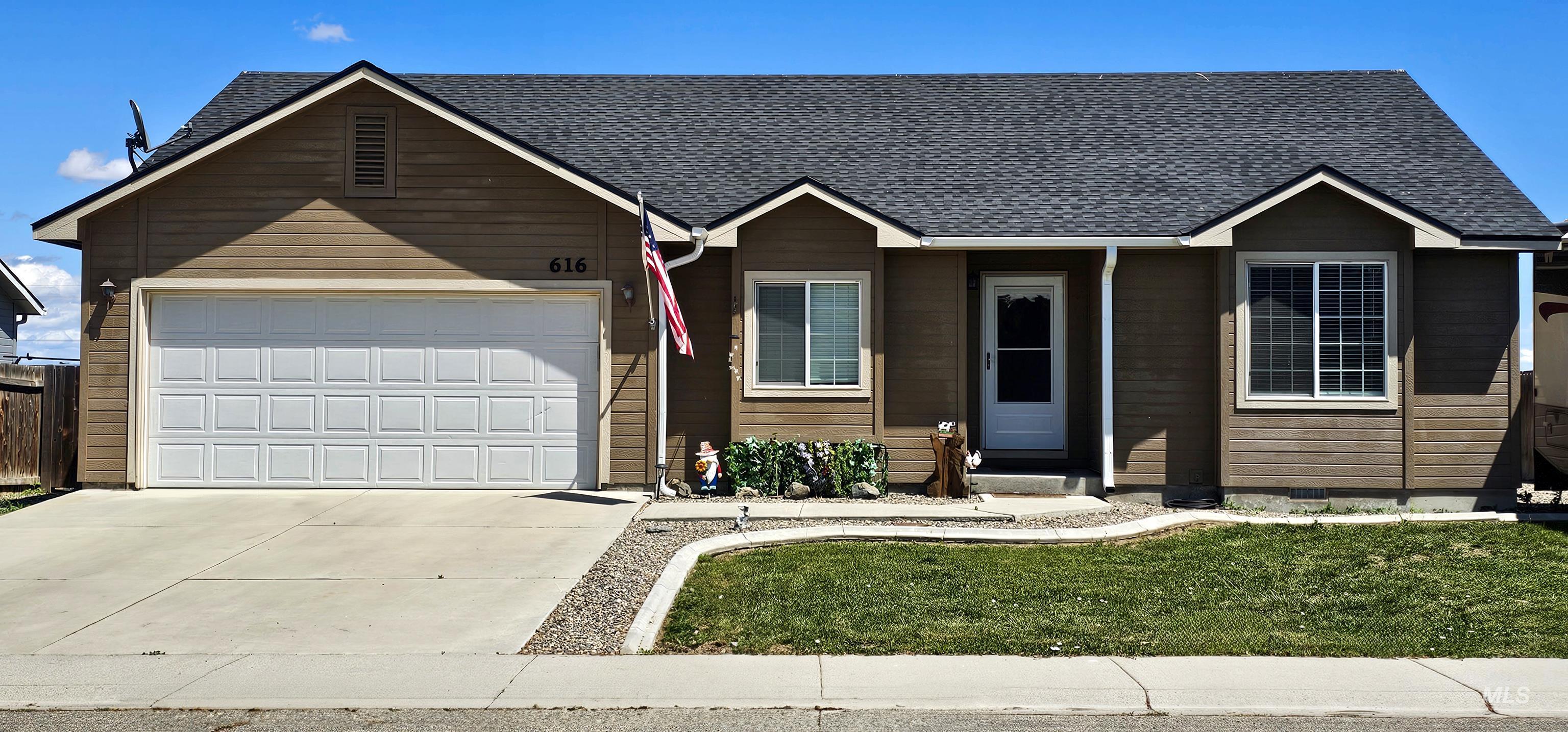 Ranch-style home featuring driveway, a garage, a shingled roof, and a front lawn