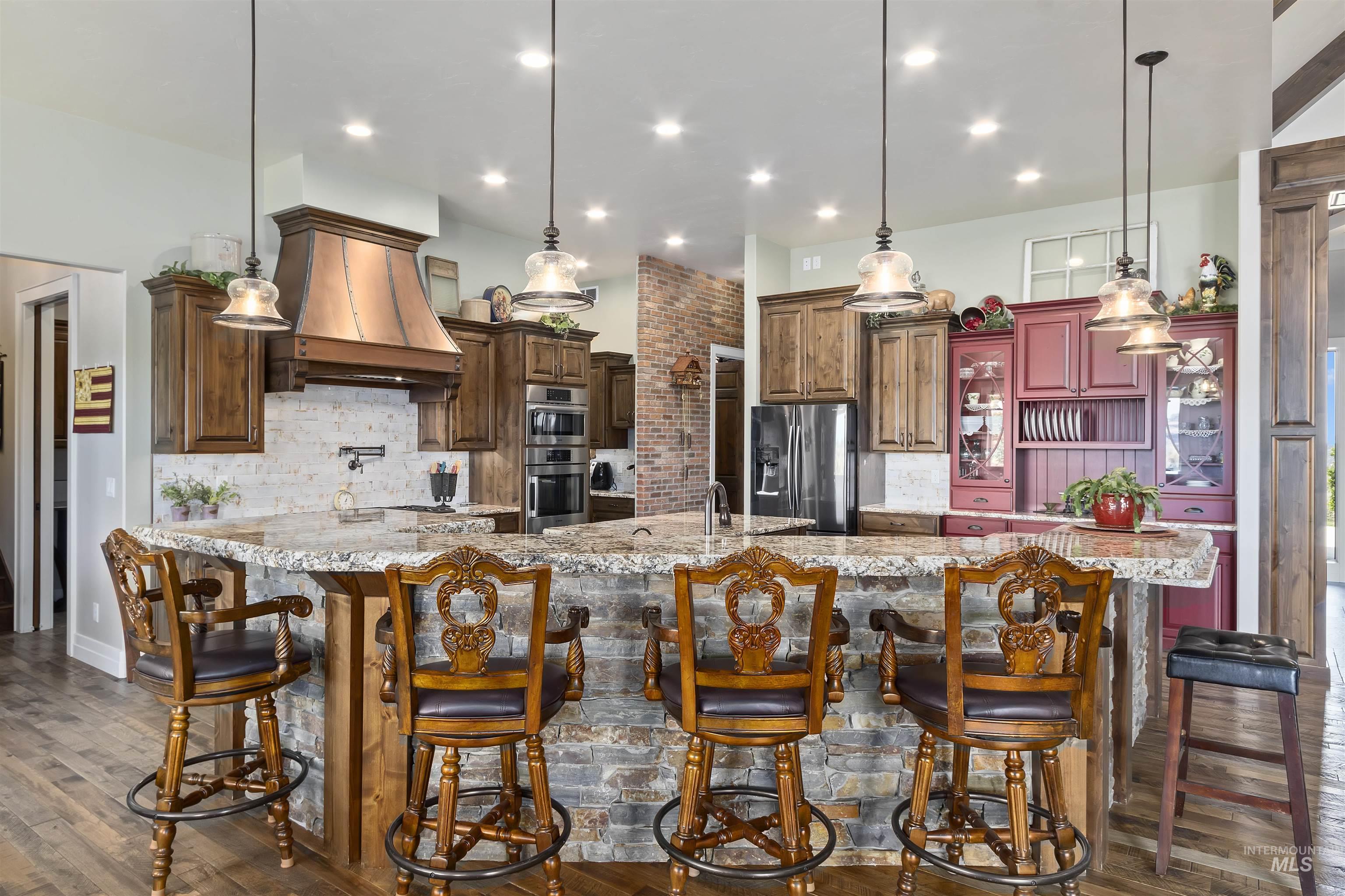 Kitchen featuring decorative backsplash, a large island, appliances with stainless steel finishes, and dark wood-style floors