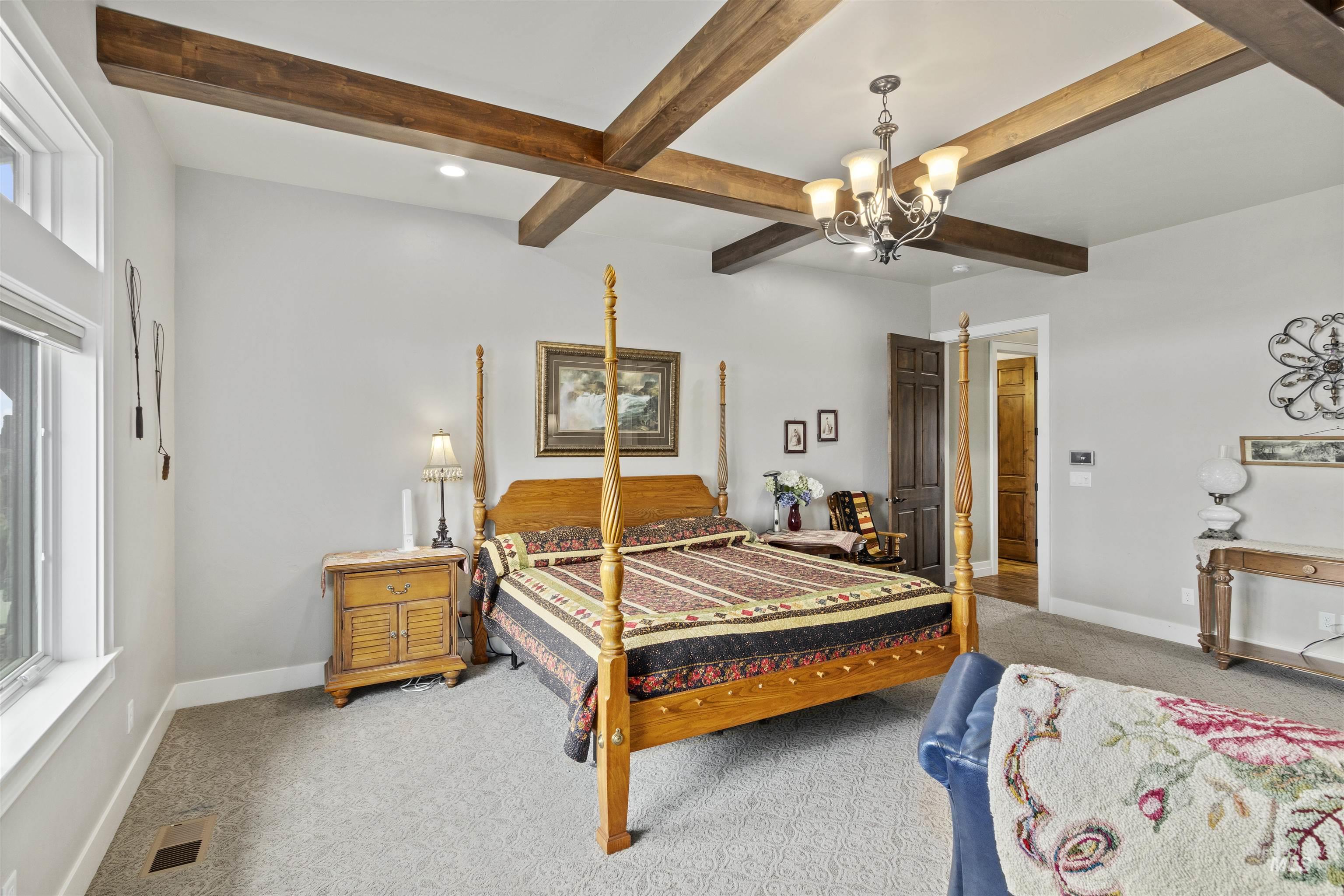 Carpeted bedroom featuring a chandelier, beam ceiling, and recessed lighting