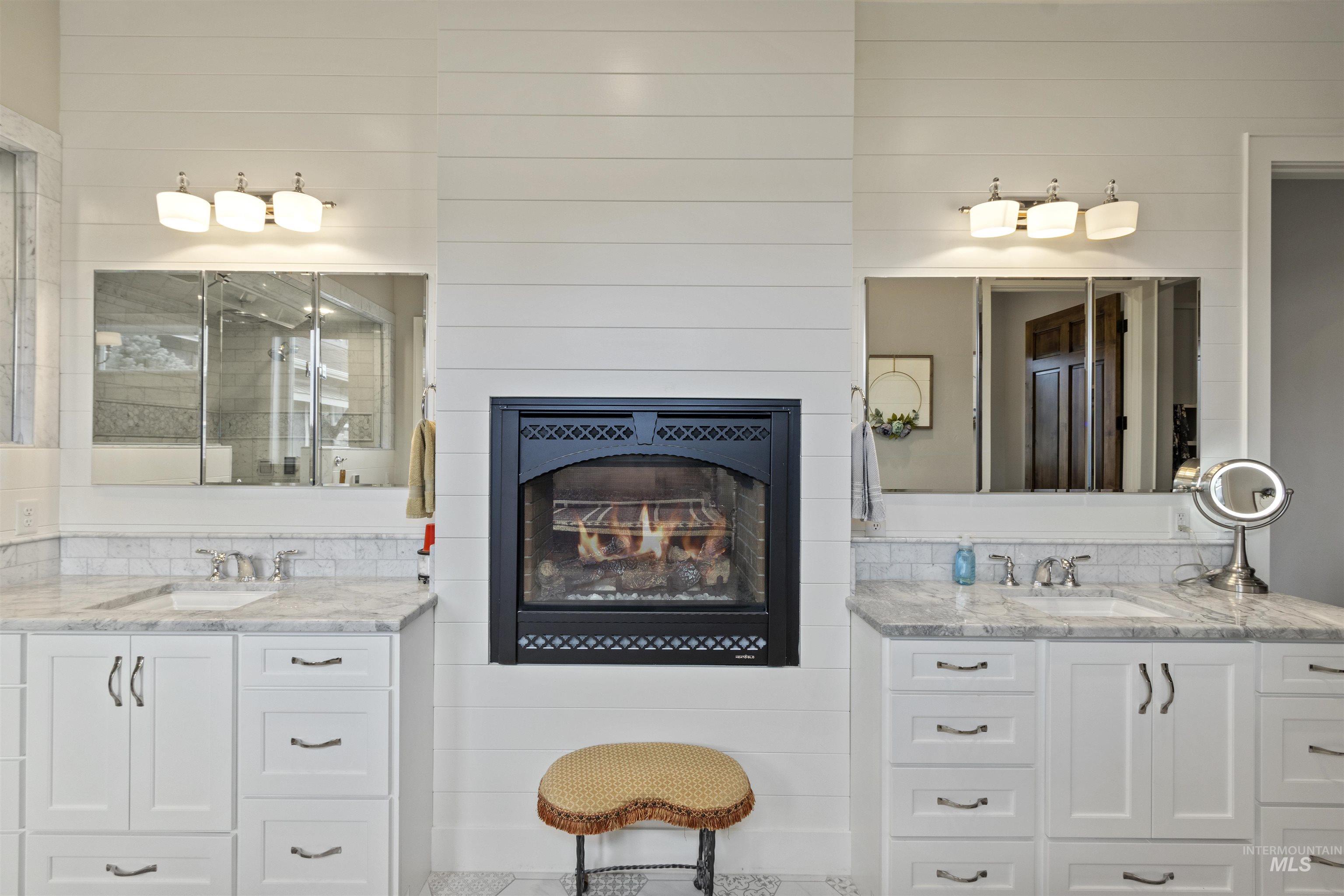 Bathroom with two vanities and a lit fireplace