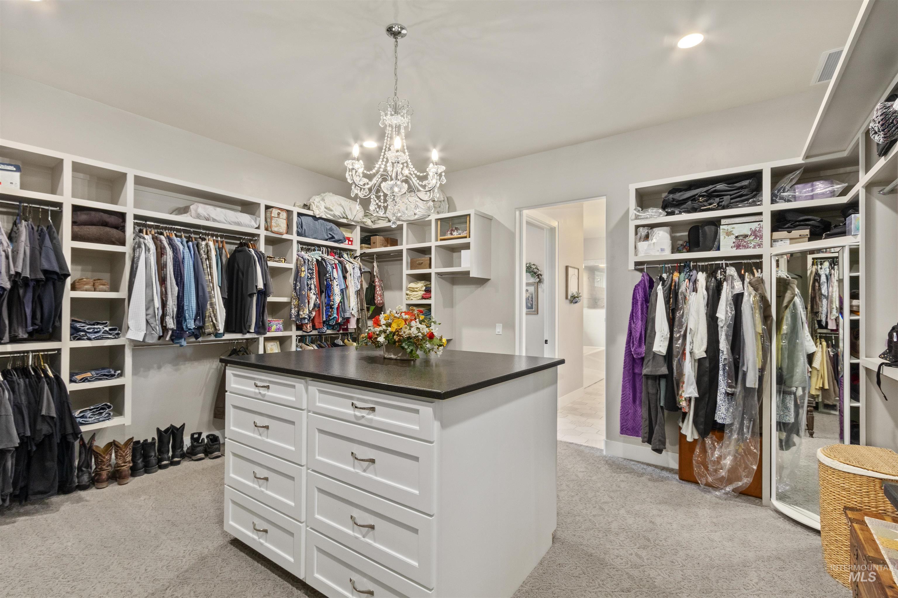 Spacious closet featuring light colored carpet and a chandelier