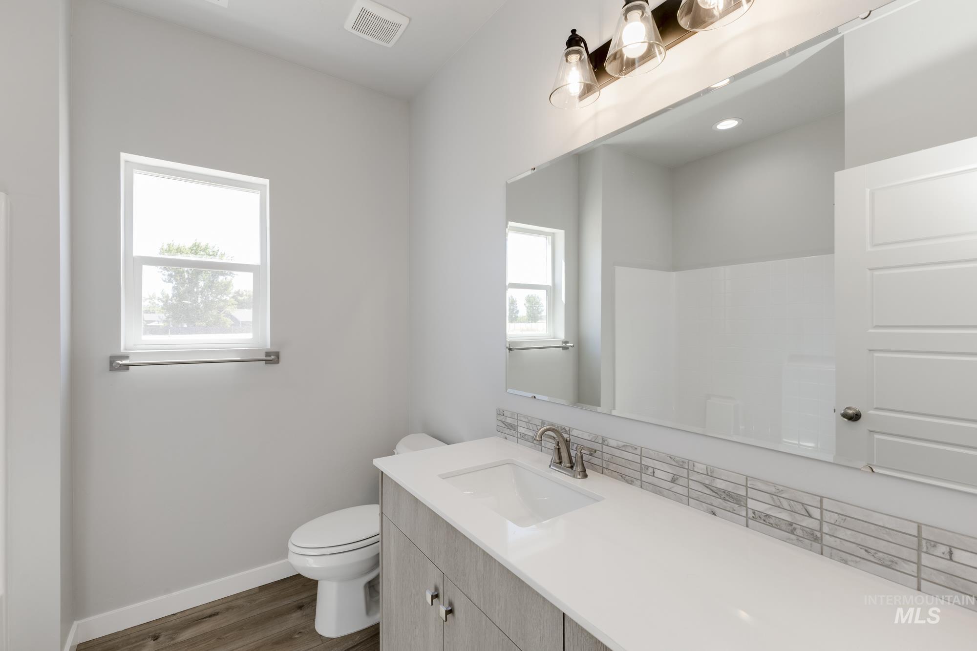 Full bathroom with vanity, wood finished floors, decorative backsplash, and a shower